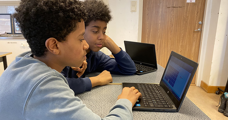 Två högstadiekillar tittar på en laptopdator.